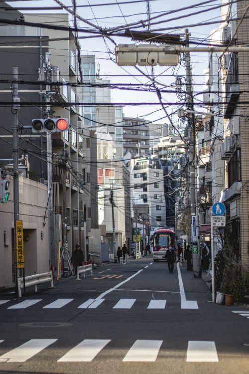 Free View of a Tokyo street featuring traffic lights, urban architecture, and pedestrians. Stock Photo