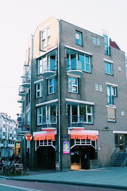 Modern building exterior featuring a bustling coffee shop on an urban street corner.
