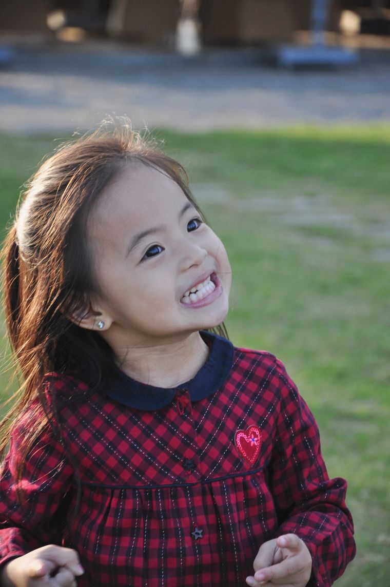 A small girl grinning in a garden — photo by Toan Nguyen on Pexels