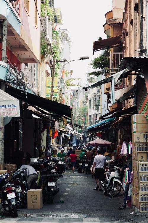 Free Busy street scene in Southeast Asia with motorbikes, shops, and people walking, provides vibrant urban life snapshot. Stock Photo