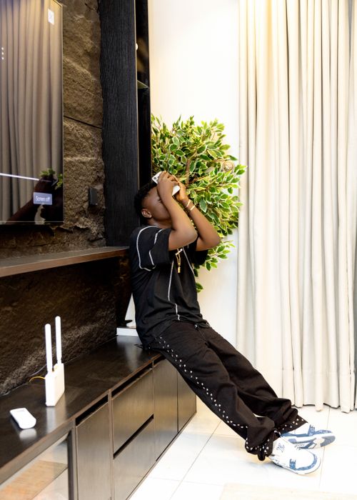 Free Casual young man in a modern indoor setting, sitting and relaxing near a TV unit. Stock Photo