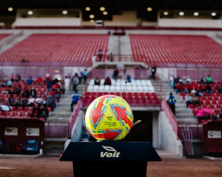 A colorful soccer ball on display at an empty stadium showcasing sports excitement.