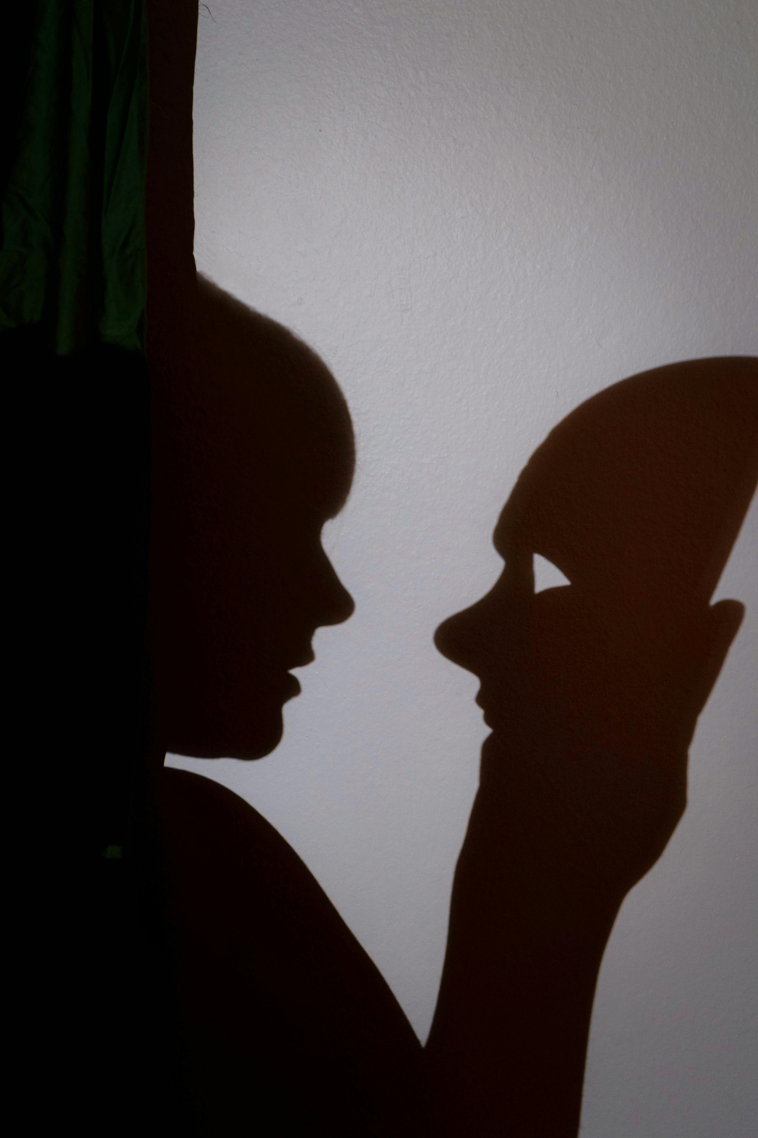 Gratis Spennende silhuett av en person som samhandler med en maske, og skaper dramatiske kunstneriske skygger. Arkivbilde