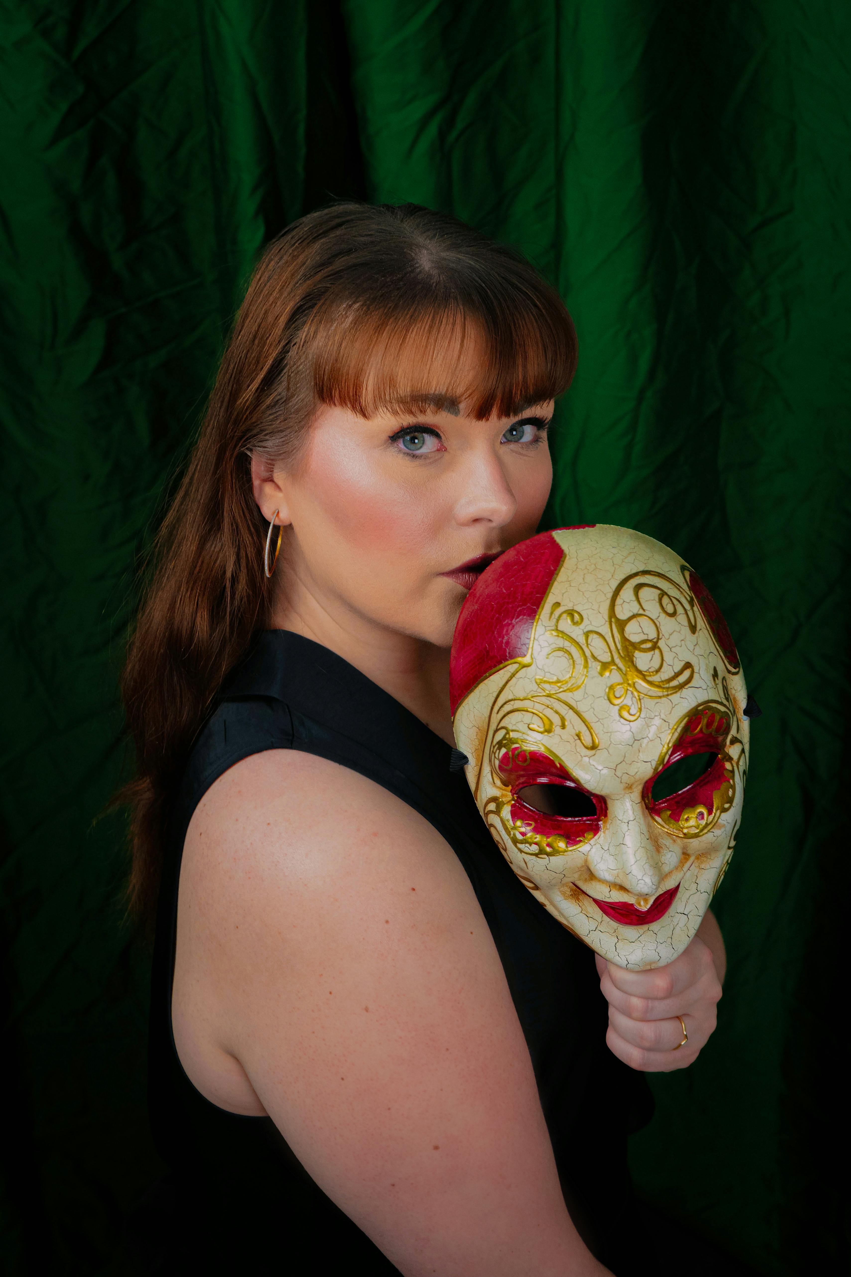 Ücretsiz Süslü bir tiyatro maskesi tutan bir kadının yer aldığı dramatik bir portre. Stok Fotoğraflar