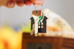 Hand holding house keys representing real estate investment with coins and wallet.