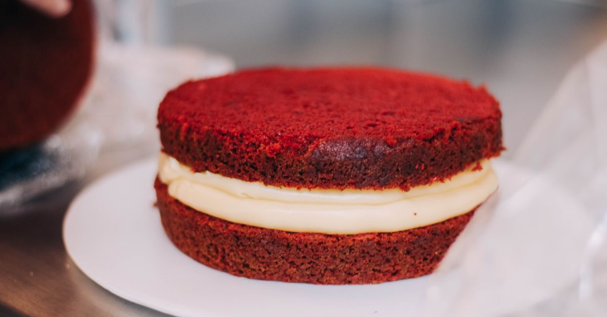 Close de um bolo red velvet com recheio de creme em um prato branco.