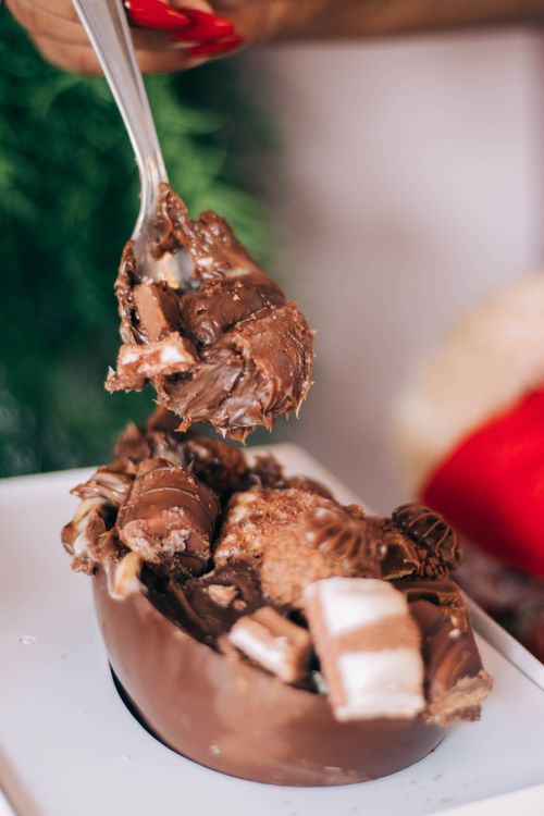 Free Indulge in a close-up view of a mouth-watering Easter egg filled with various chocolates. Stock Photo
