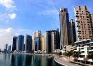 蓝天下，高耸的摩天大楼倒映在平静的码头水域中