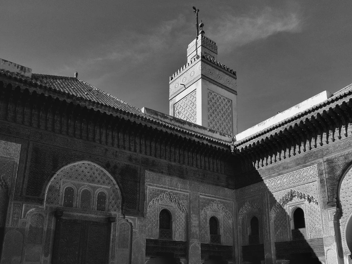 Courtyard and minaret of a Marinid madrasa in the Fes medina, in black and white