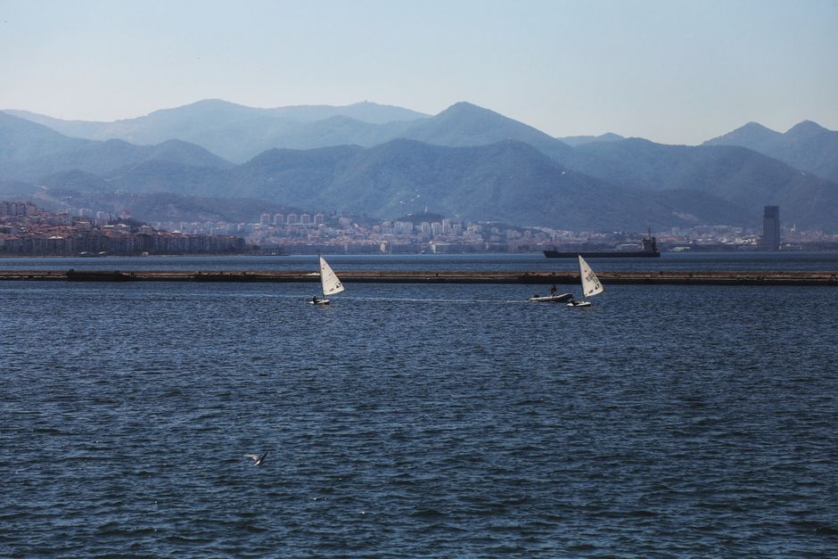 Sailboats navigating the serene Aegean Sea with İzmir's stunning mountainous backdrop.