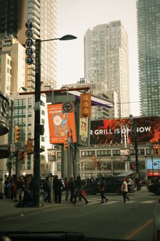 Urban scene at a busy Toronto intersection with towering skyscrapers and vibrant billboards.