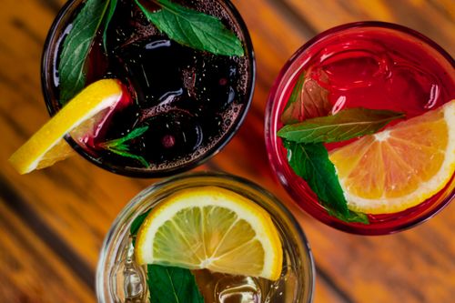 Free Top view of colorful citrus beverages garnished with lemon slices and mint leaves, perfect for summer refreshment. Stock Photo