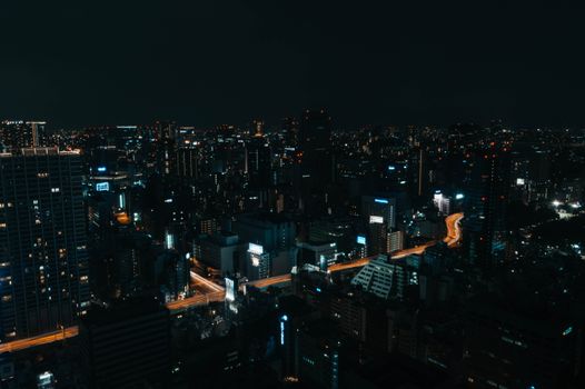 Aerial view of Tokyo city lights illuminating the night with glowing streets and skyscrapers.