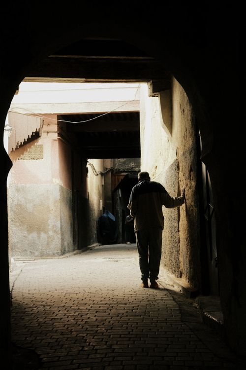 Free Silhouette of a person walking through an ancient arched alleyway, capturing mystery and history. Stock Photo