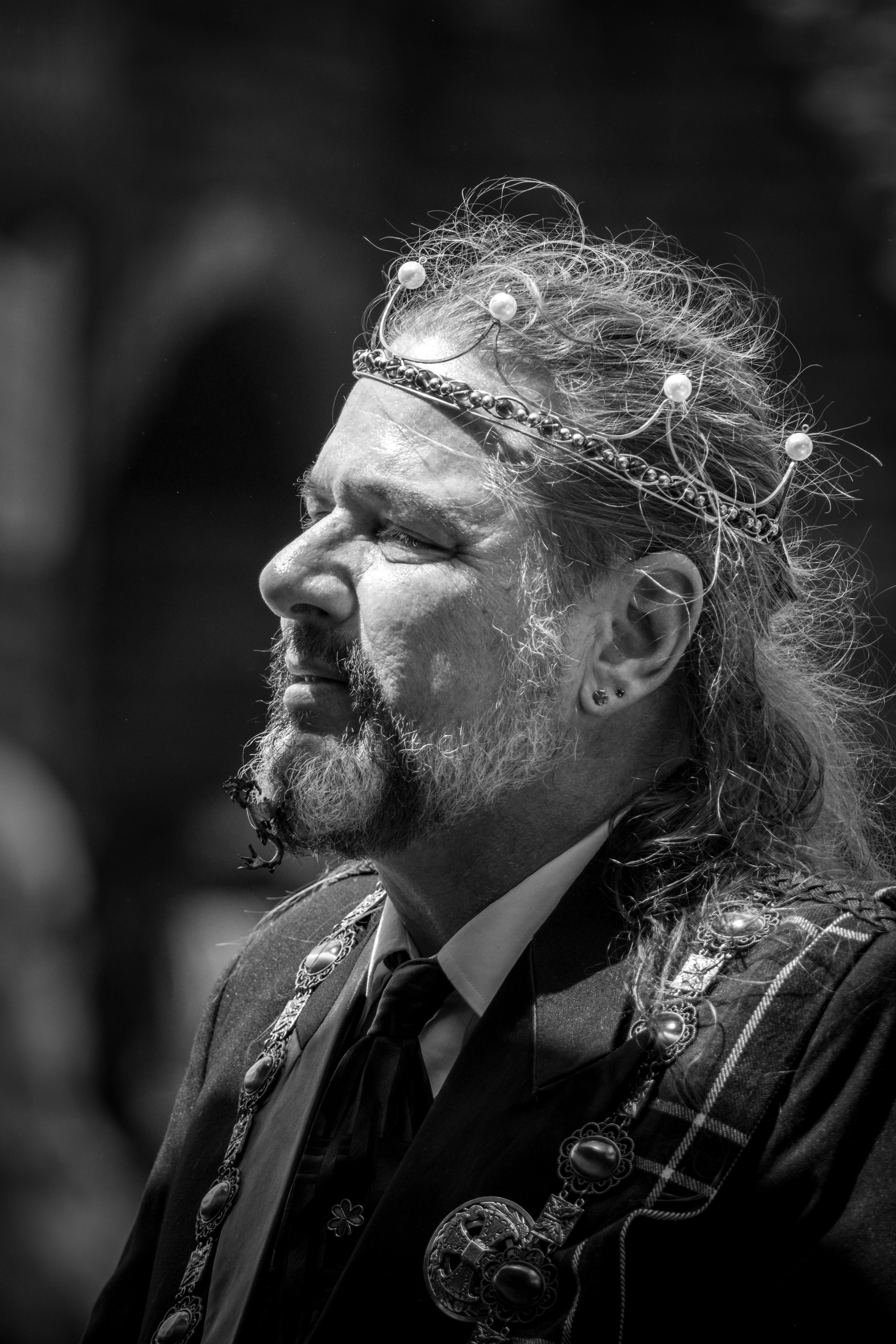 A distinguished man with a crown is captured in a striking black and white portrait.