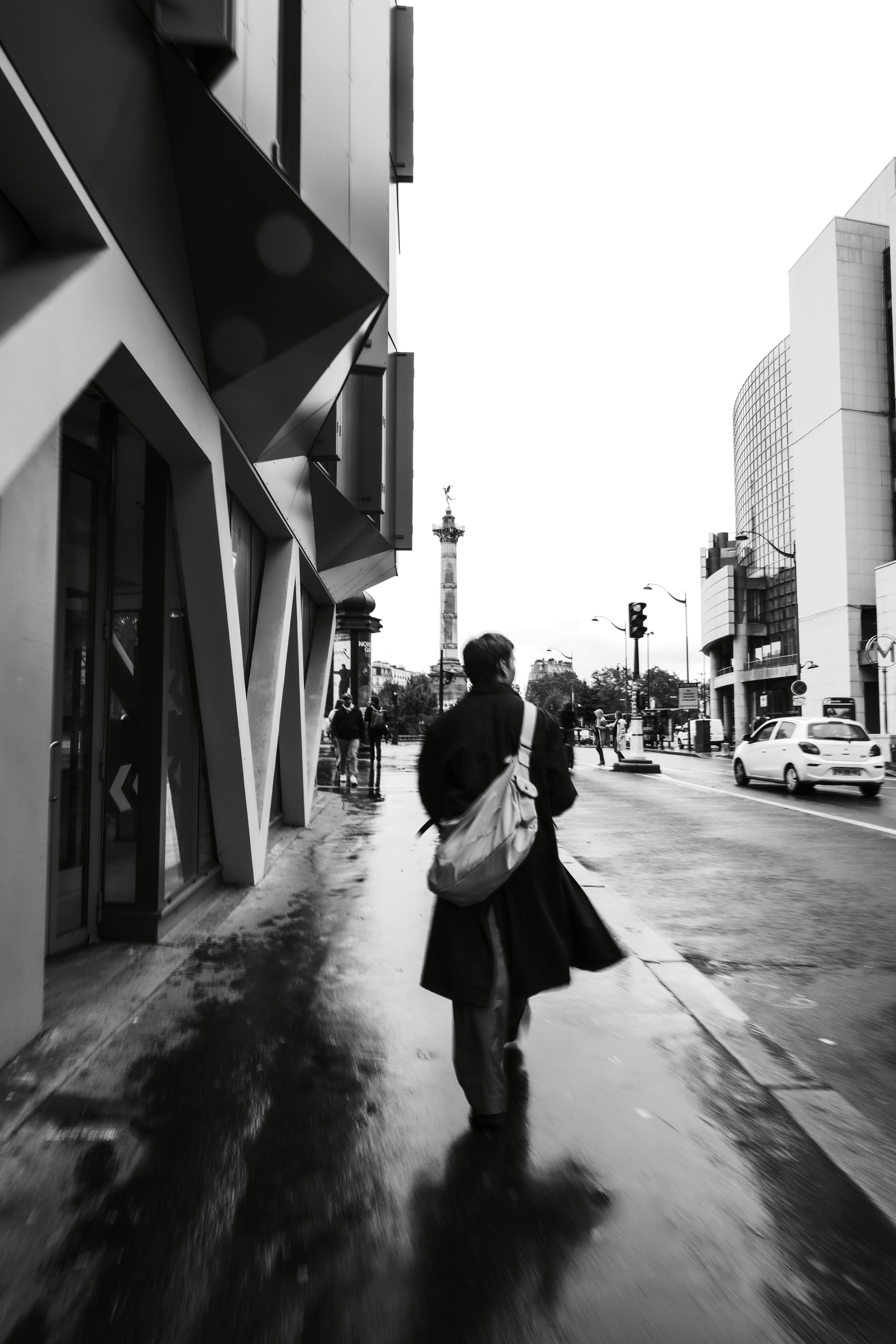 Black and white photograph of a person walking on a rainy street in Paris, France.