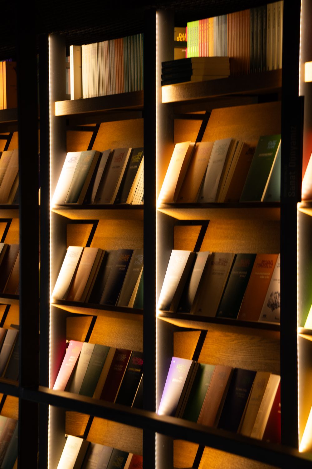 Illuminated bookshelves in a cozy library setting · Free Stock Photo