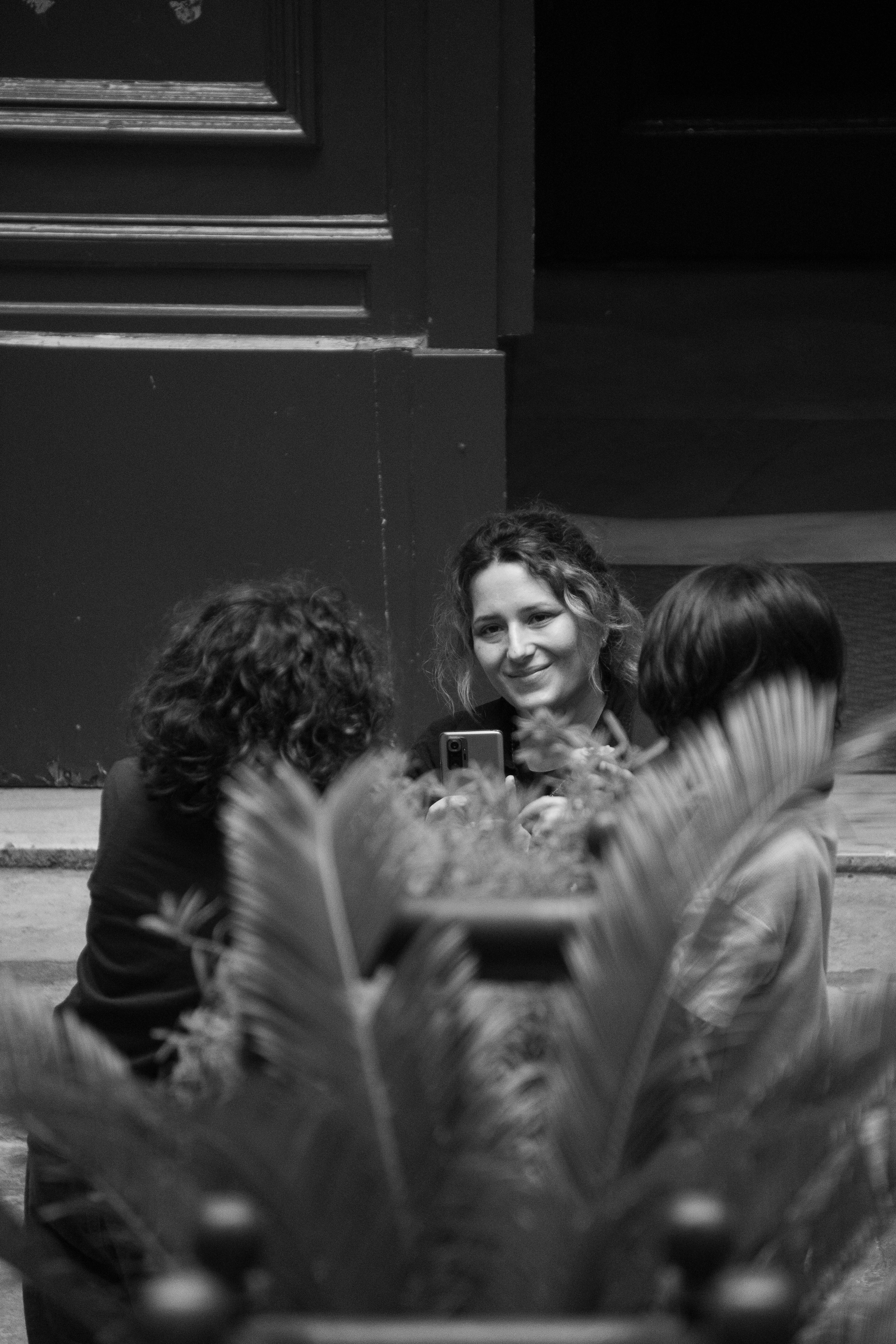 bezplatná Tři přátelé se zapojili do živého rozhovoru venku, zachyceného v monochromatickém režimu. Základová fotografie