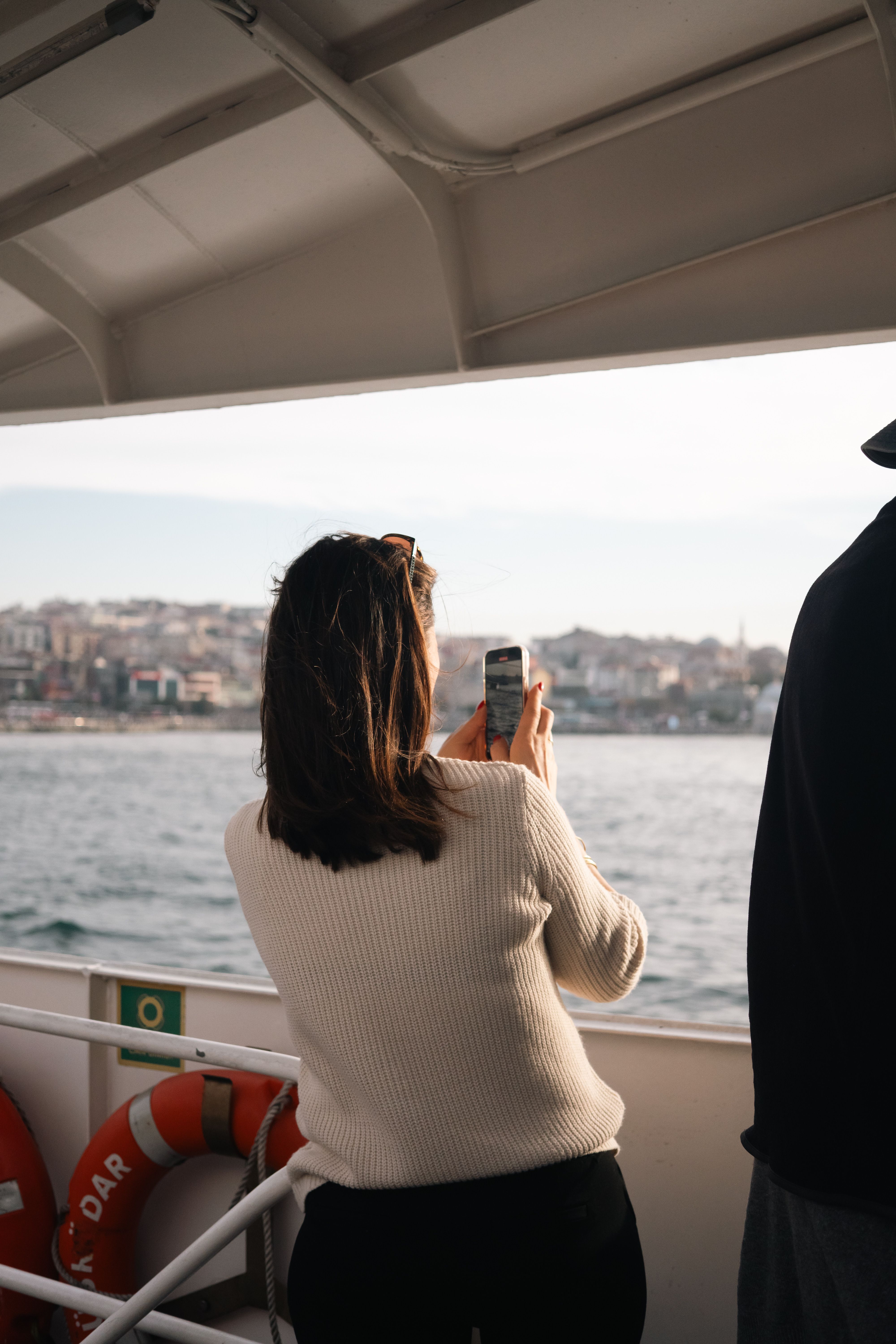 Woman on a Boat Captures Scenic City View · Free Stock Photo
