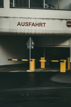 Concrete parking garage exit in Wurzburg with 'Ausfahrt' sign and barrier.