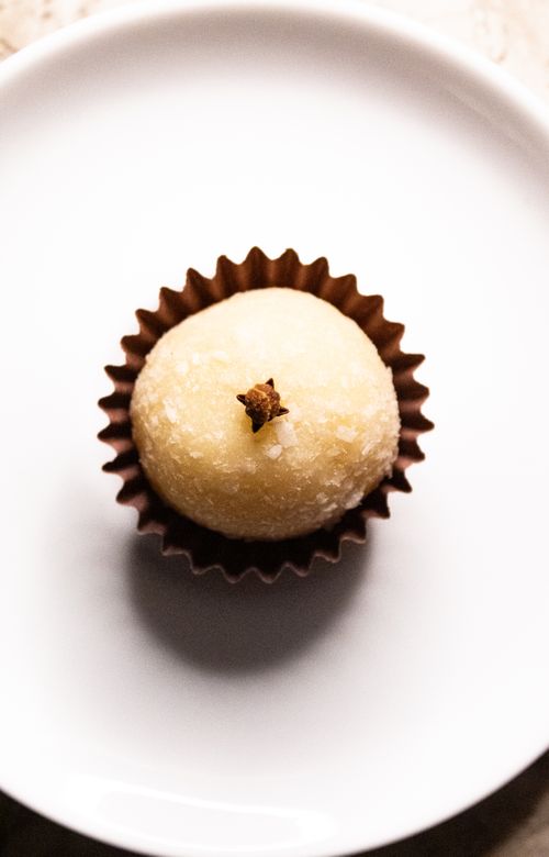 Free A beautifully presented coconut truffle with a clove, perfect for gourmet food presentations. Stock Photo