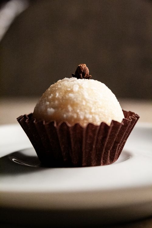 Free A close-up of a gourmet coconut truffle topped with a clove, presented elegantly on a plate. Stock Photo