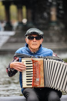 Senior man playing accordion by a fountain in New York City.