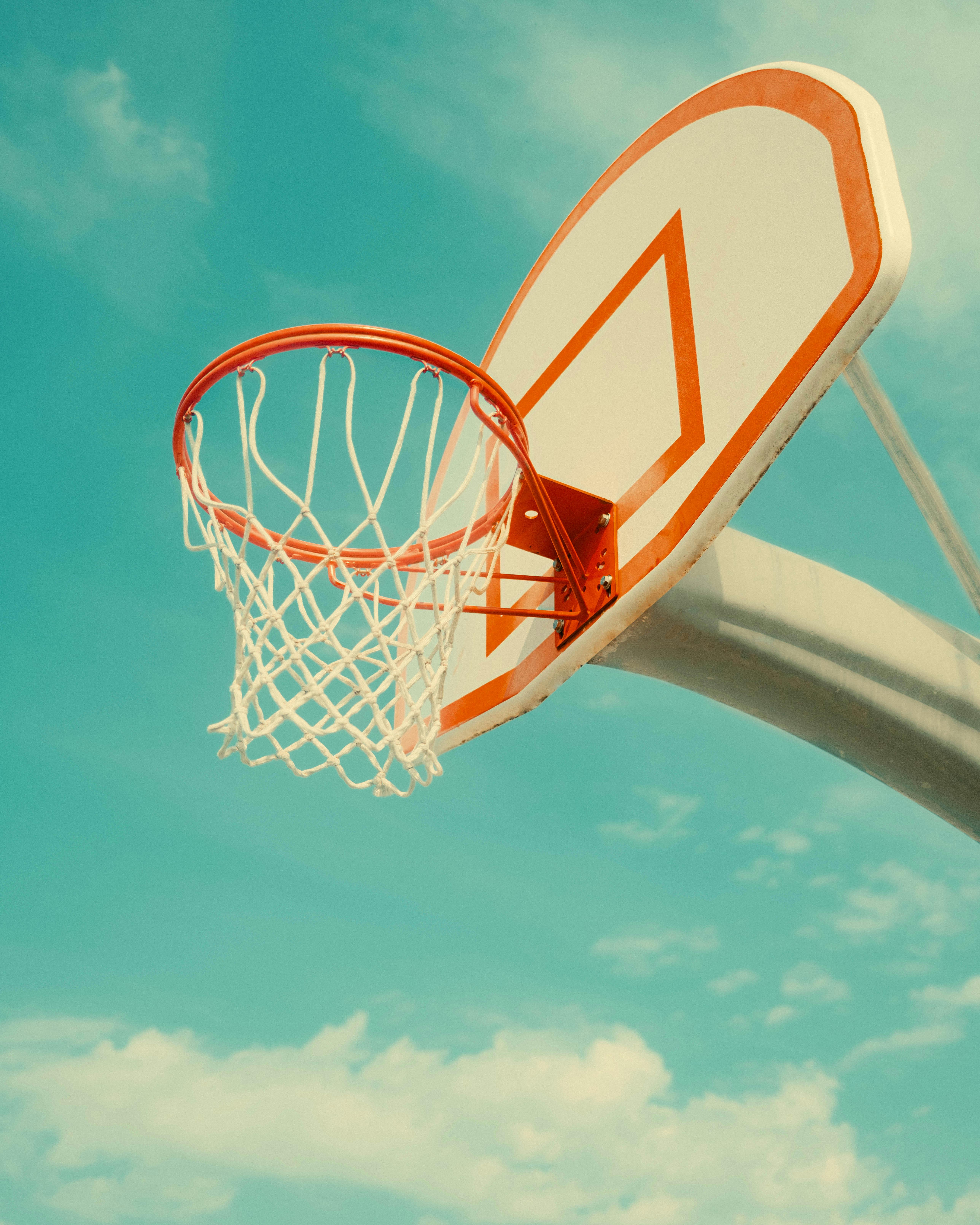 A basketball hoop with net against a clear blue sky in daylight.