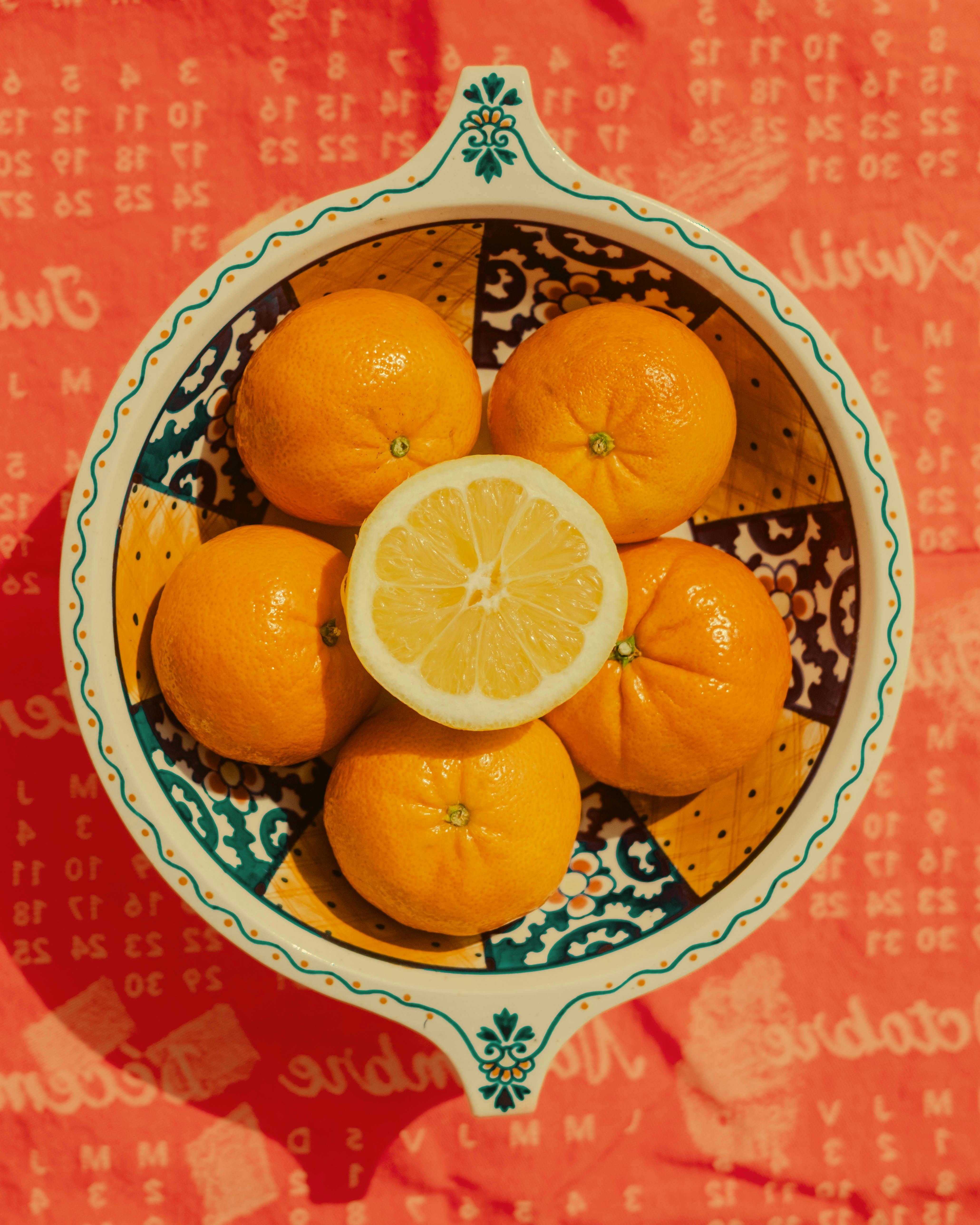 Colorful citrus fruits arranged in a patterned bowl on a textured surface, perfect for bright and vibrant visuals.