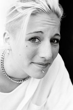 Captivating black and white portrait of a smiling adult woman with short hair and piercings.