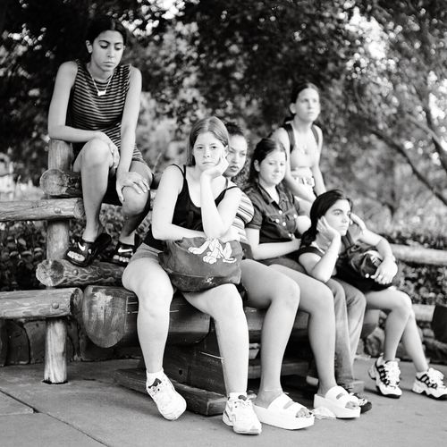 Free A candid black and white photo of teenagers resting outdoors on a bench at Miami Beach park. Stock Photo