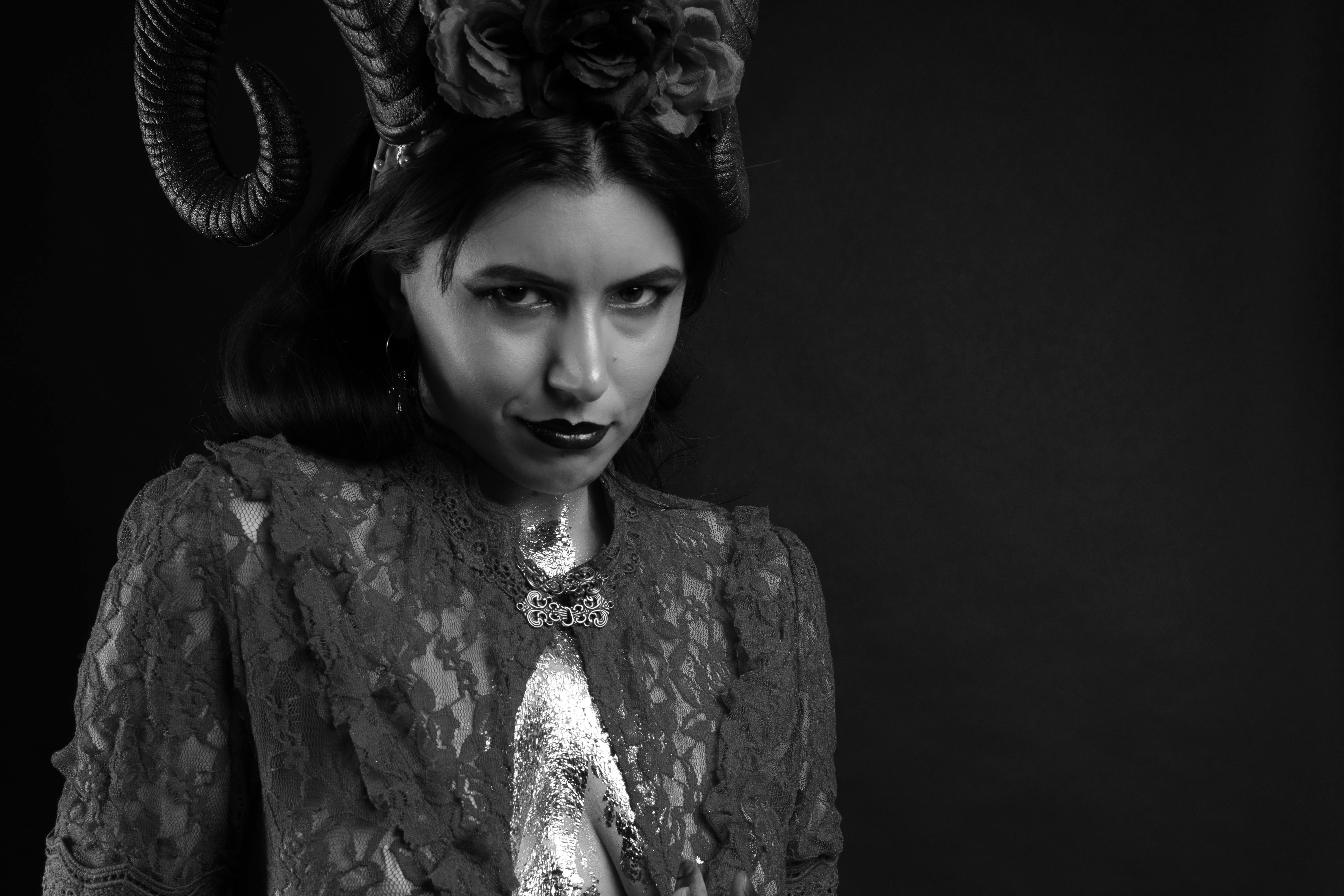 grátis Uma mulher em traje gótico com chifres elaborados, exalando mistério em preto e branco. Foto profissional