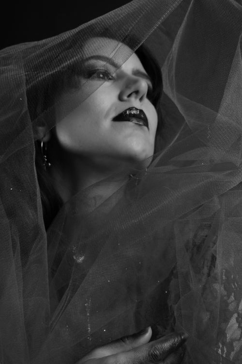 Free Dramatic black and white portrait of a woman enveloped in a veil, exuding elegance and mystery. Stock Photo