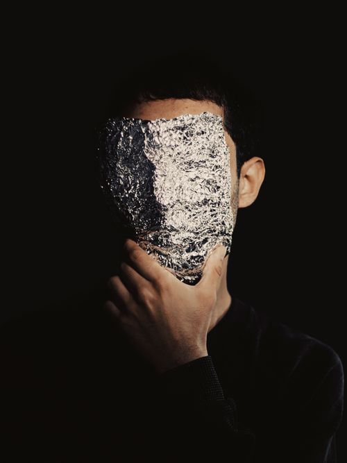 Free An enigmatic portrait of a person with face covered by foil, creating introspective mood. Stock Photo