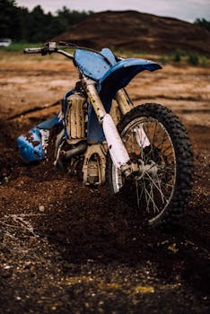 一辆蓝色的泥土自行车卡在户外小路的泥泞地形中，凸显了越野摩托车的挑战