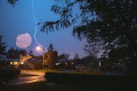 夜晚，一道耀眼的闪电照亮了树木环绕的宁静郊区街道