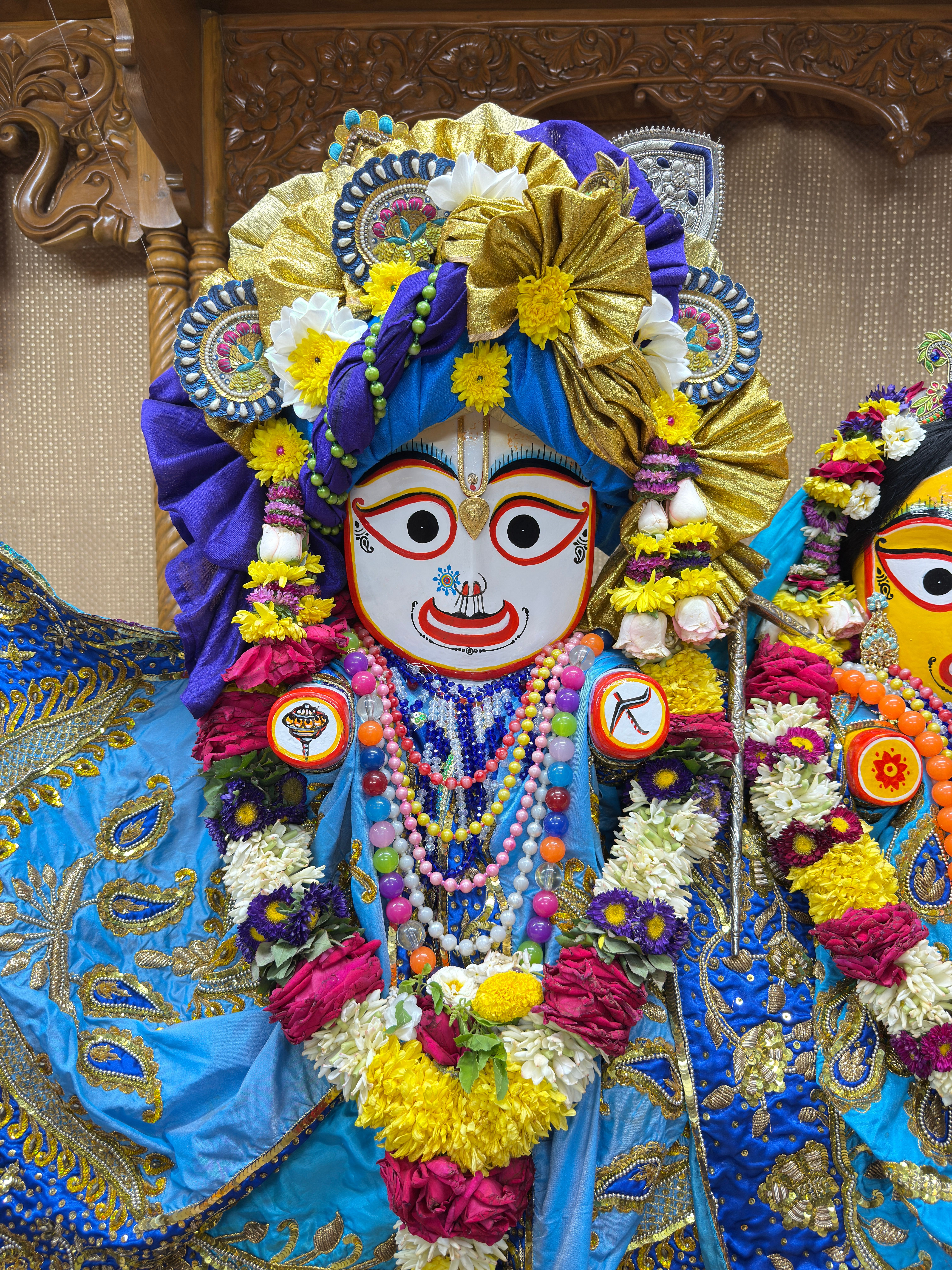 Colorful Hindu deity statue adorned with vibrant flowers and jewels, showcasing cultural artistry.