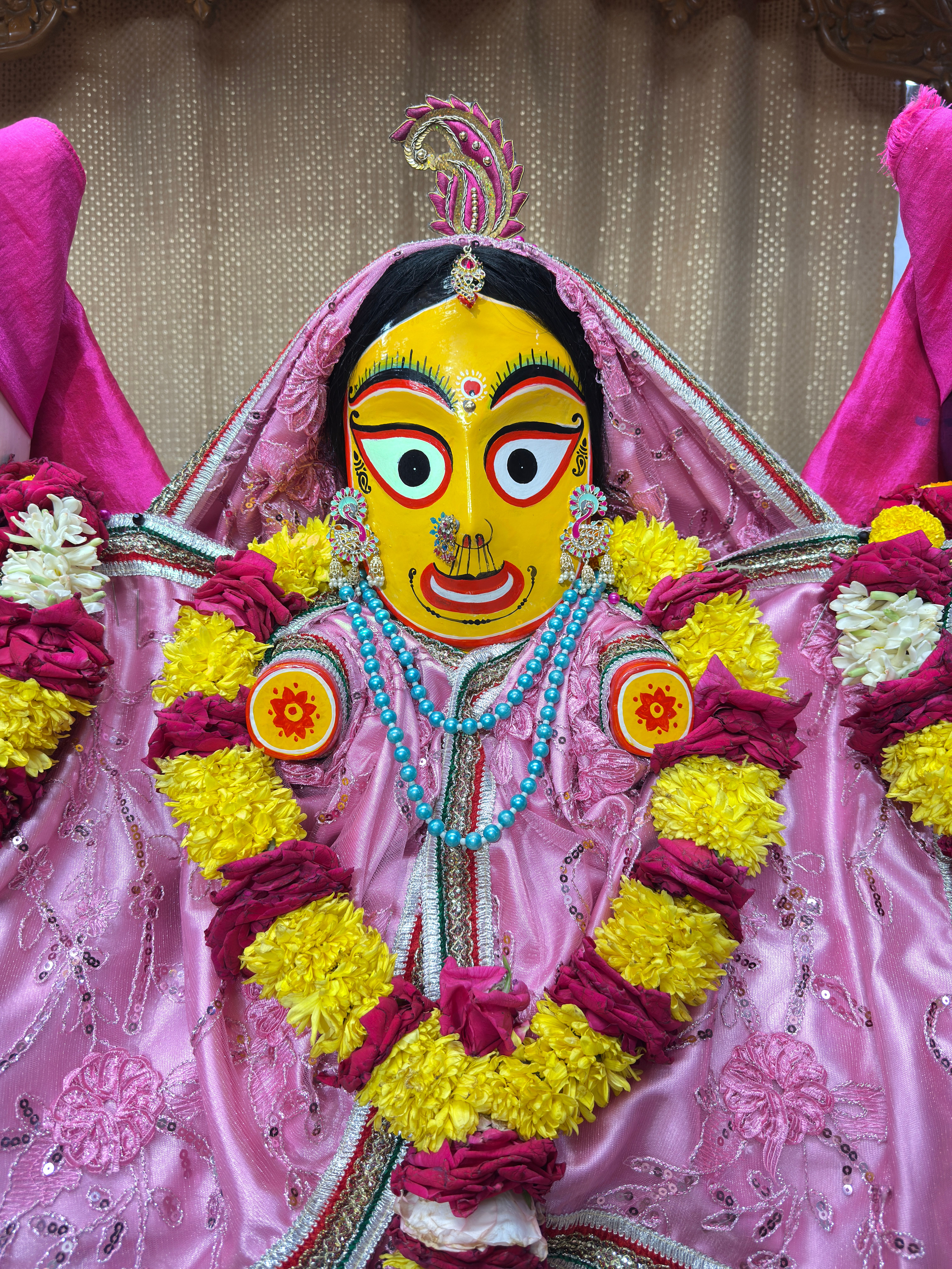 Vibrant Indian statue adorned with flowers and intricate garments, showcasing cultural artistry.