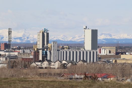 Industrial area in Calgary with Rocky Mountains backdrop, showcasing urban development.