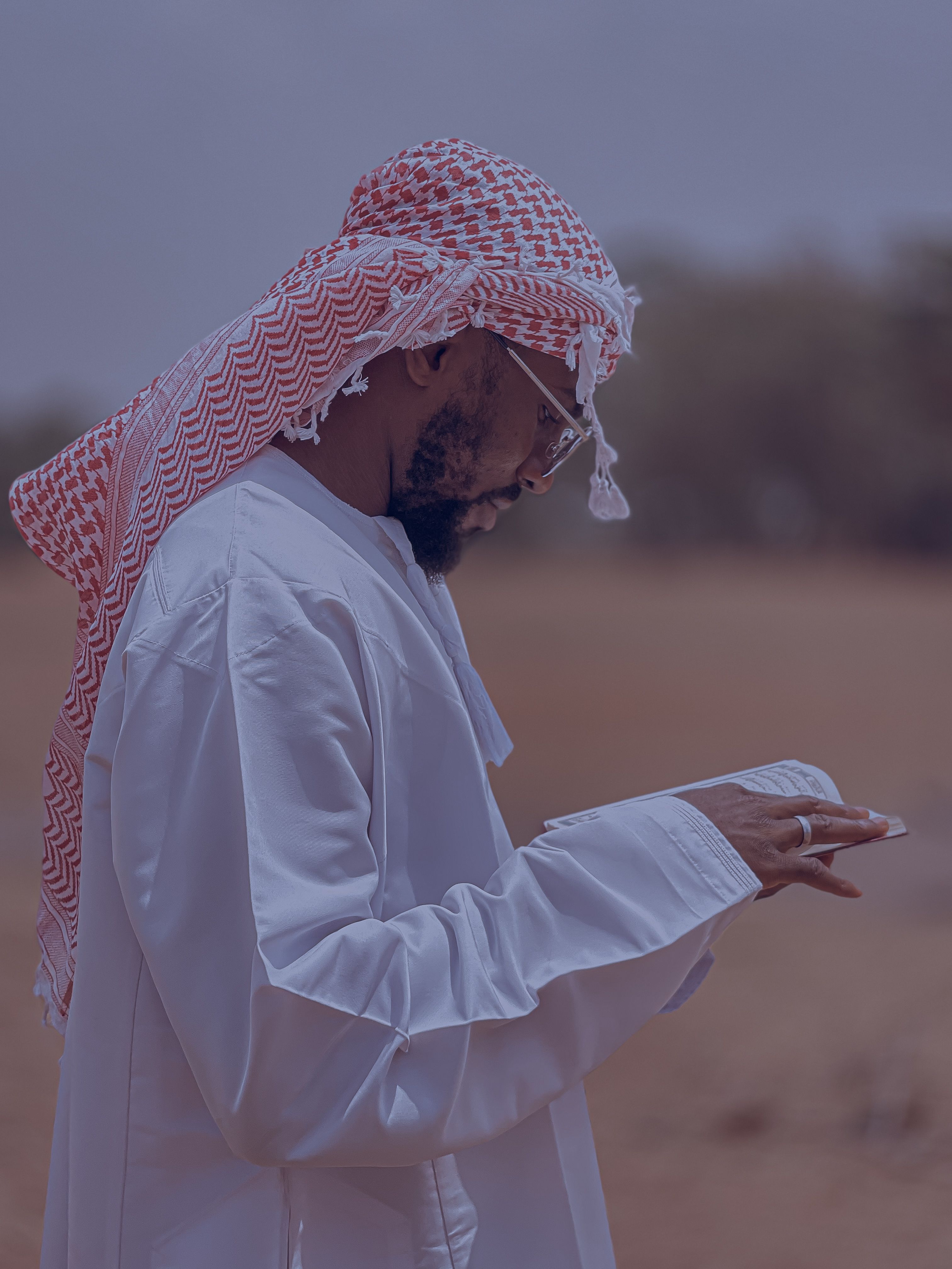 Middle Eastern man in traditional attire using smartphone outdoors, focusing on technology integration.