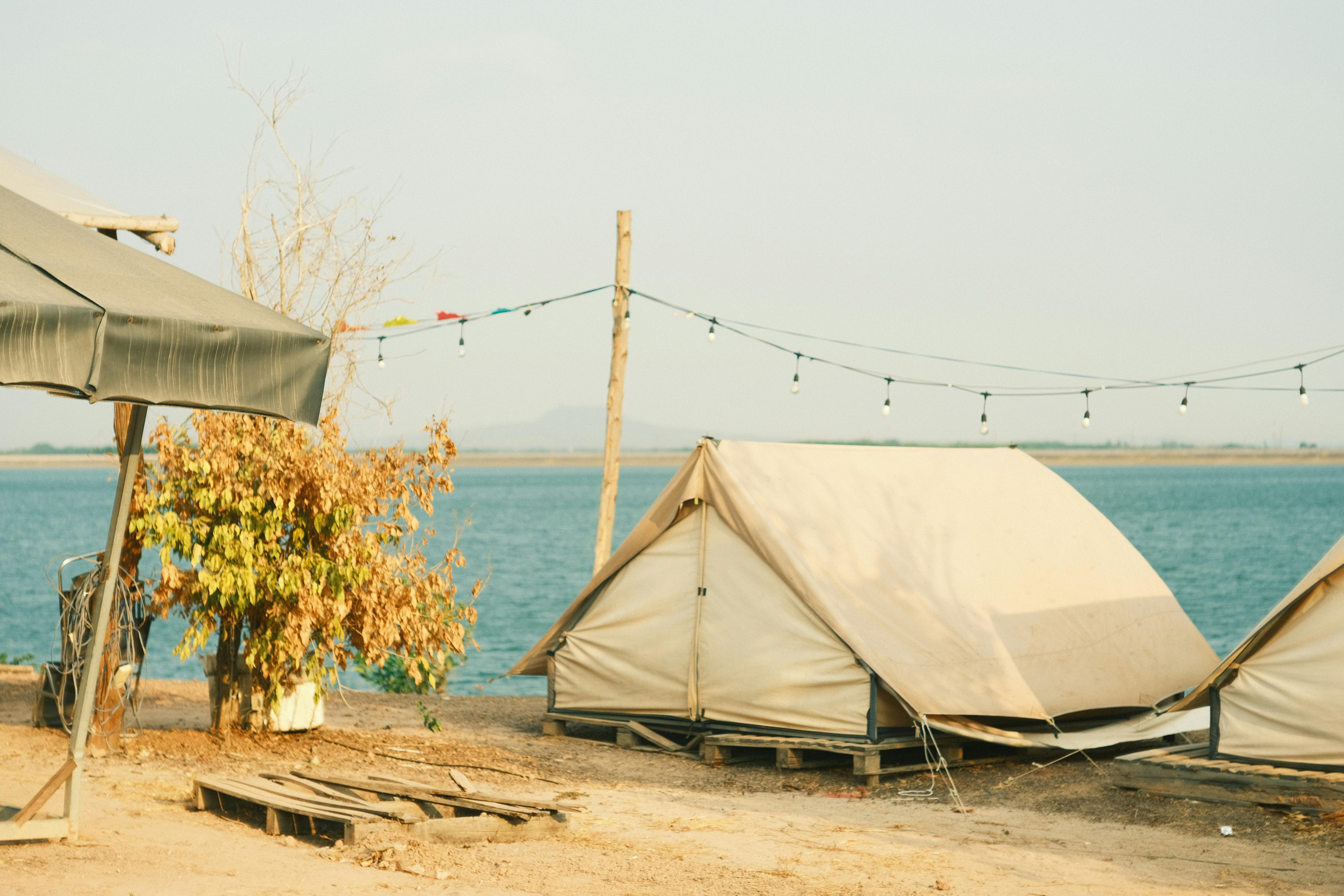 Serene camping setup by the river with tents under string lights.