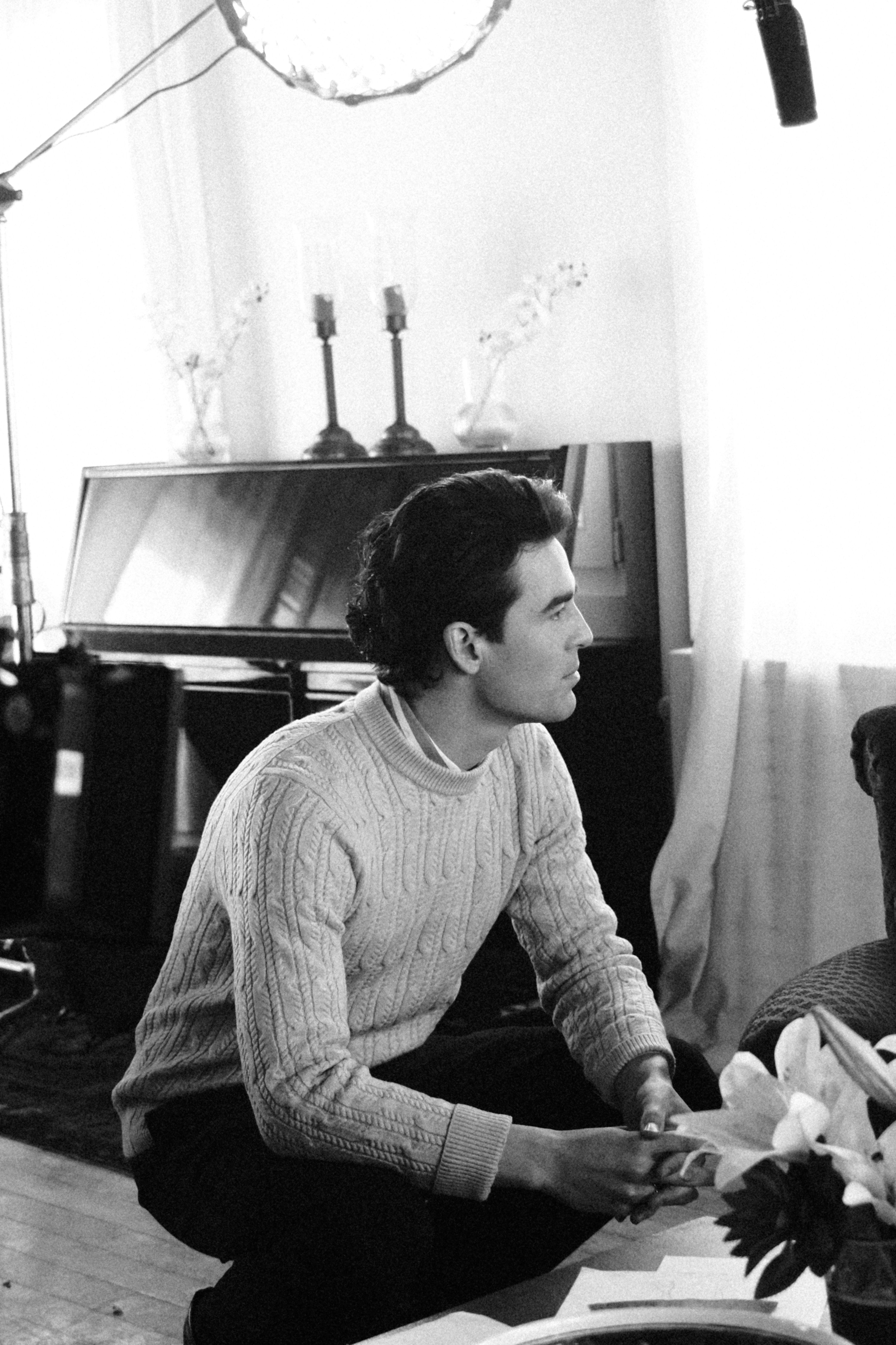 A contemplative man sitting indoors in a classic B&W portrait setting.