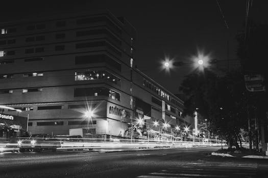 Dramatic urban night photo featuring long exposure light trails and illuminated buildings.