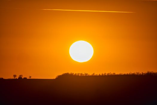 A stunning sunset over rolling hills in Pepin, Wisconsin, with a vibrant orange sky.