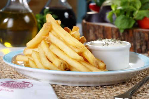 Free Crispy golden French fries served with a creamy dip in a cozy setting. Stock Photo