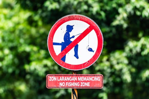 A close-up of a no fishing zone sign against lush green foliage, emphasizing environmental protection.