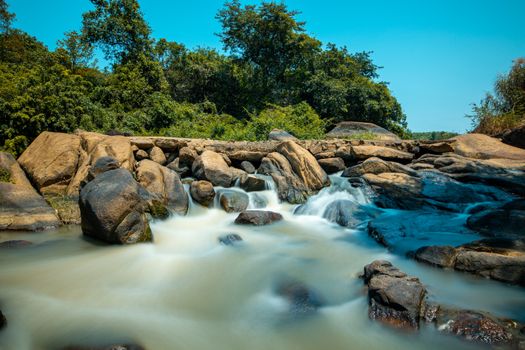 A tranquil waterfall flowing over rocks in a vibrant forest landscape.