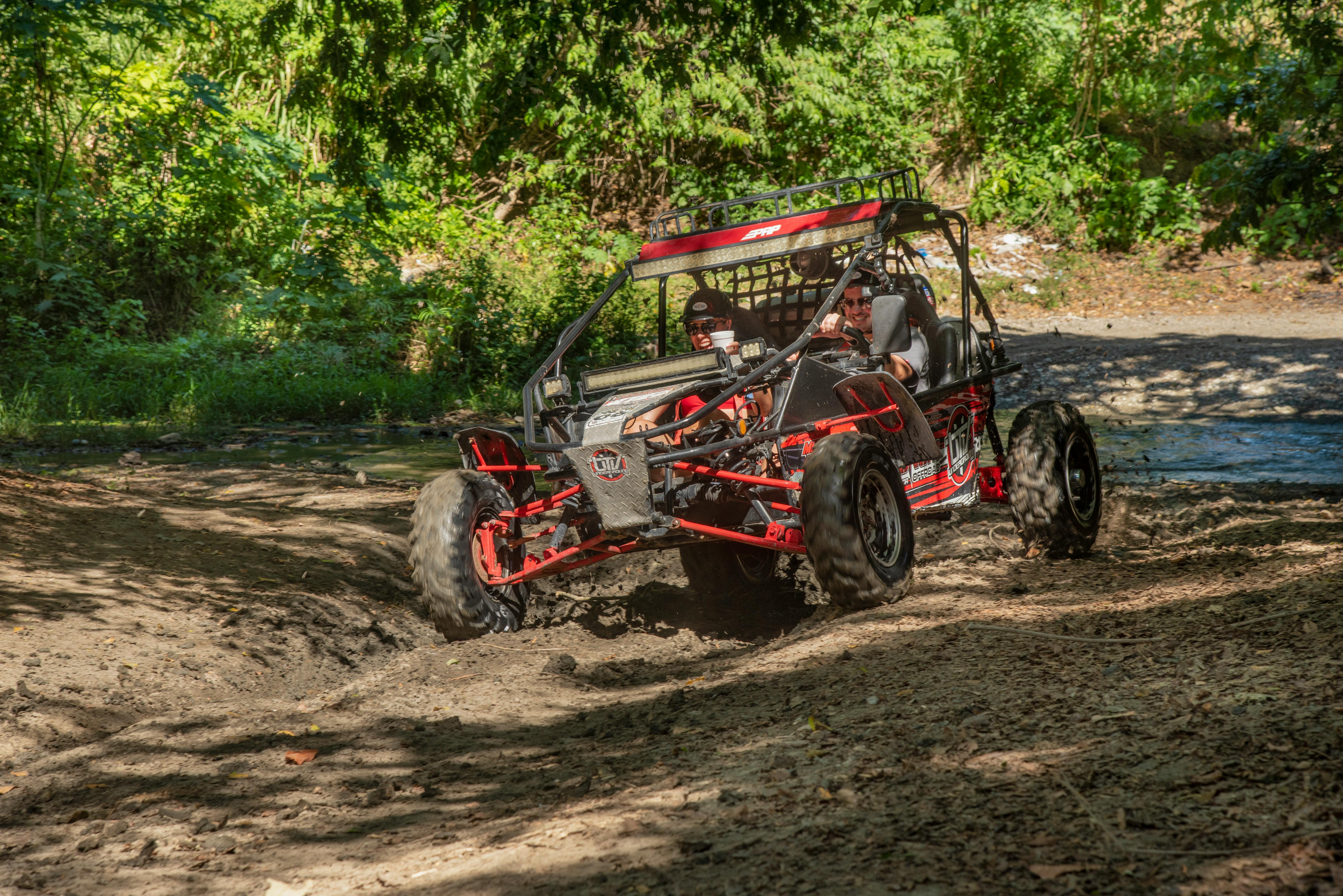 Two people enjoying dune buggy adventure in wooded terrain.