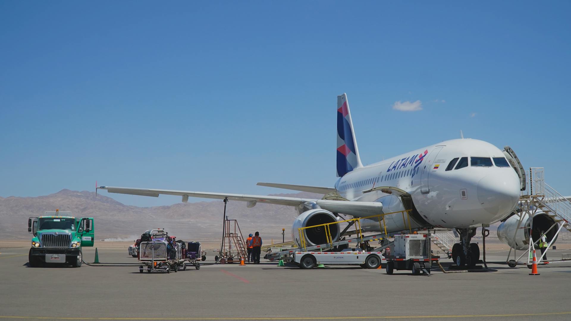 Airplane on tarmac at Chilean airport with desert background and clear skies.