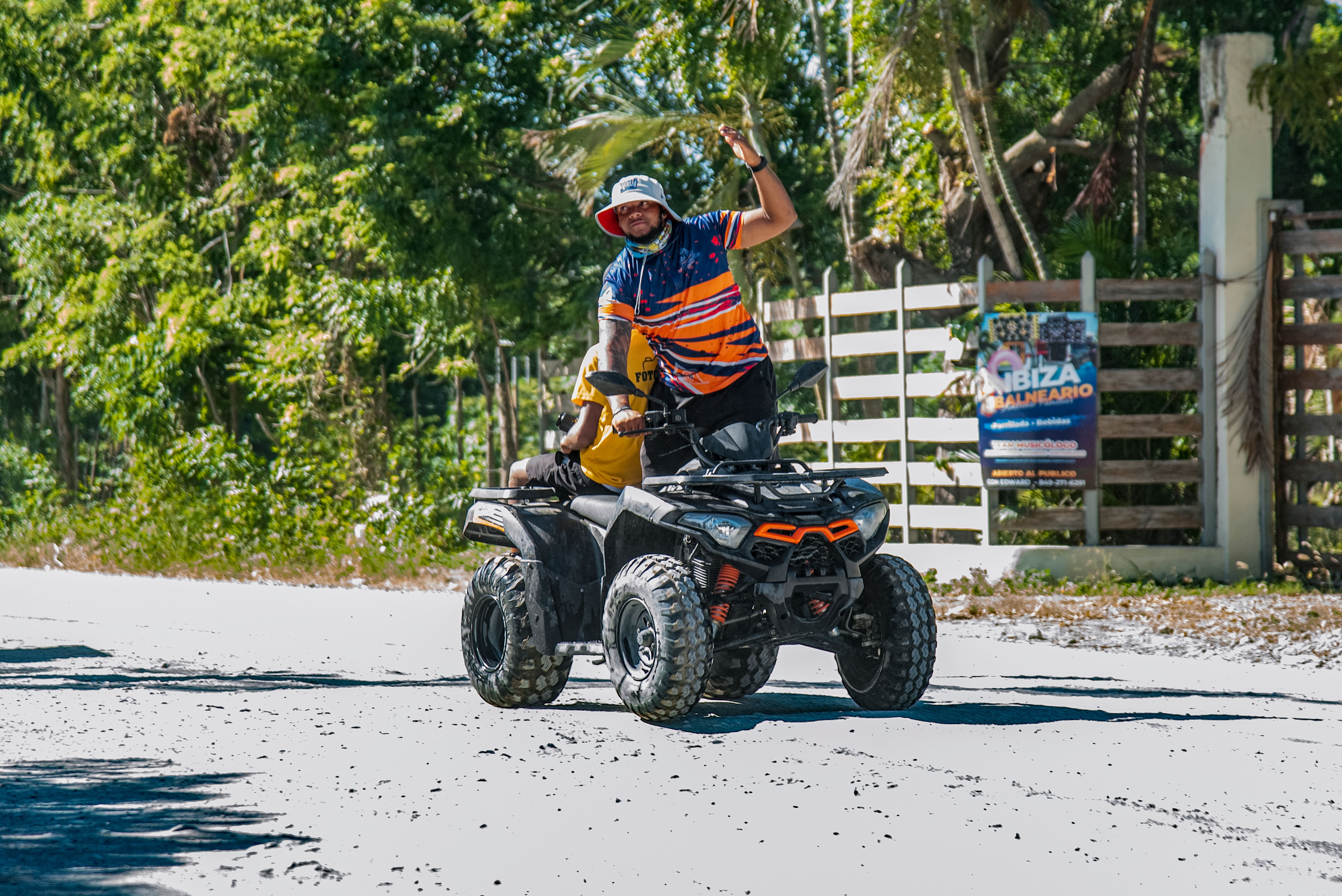 Man Riding ATV in Tropical Setting Waving · Free Stock Photo